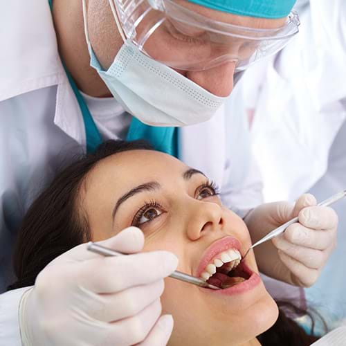 A dentist checking on a woman's teeth for cavities