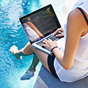 Girl on laptop by the pool
