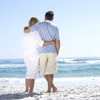 A couple staring out at the waves on the beach.